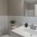 Large well lit bathroom with large mirror and white cabinets .