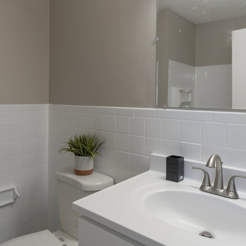 Bathroom Large well lit bathroom with large mirror and white cabinets .